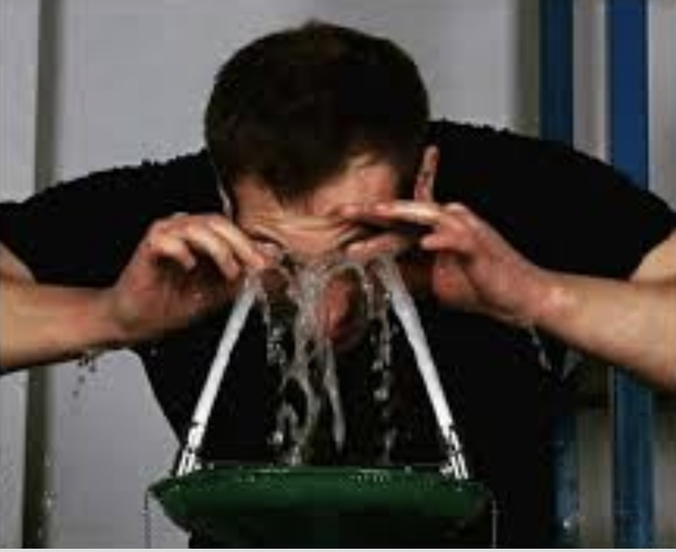 Người đàn ông rửa mắt dưới hai vòi nước